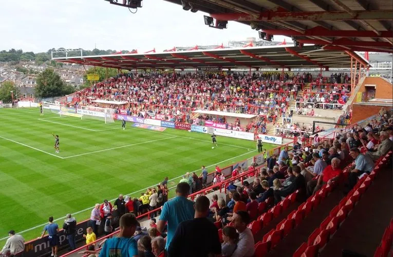 Bầu không khí sôi động của St. James Park Exeter vào một ngày thi đấu, khán giả chờ đợi trận đấu đầy kịch tính