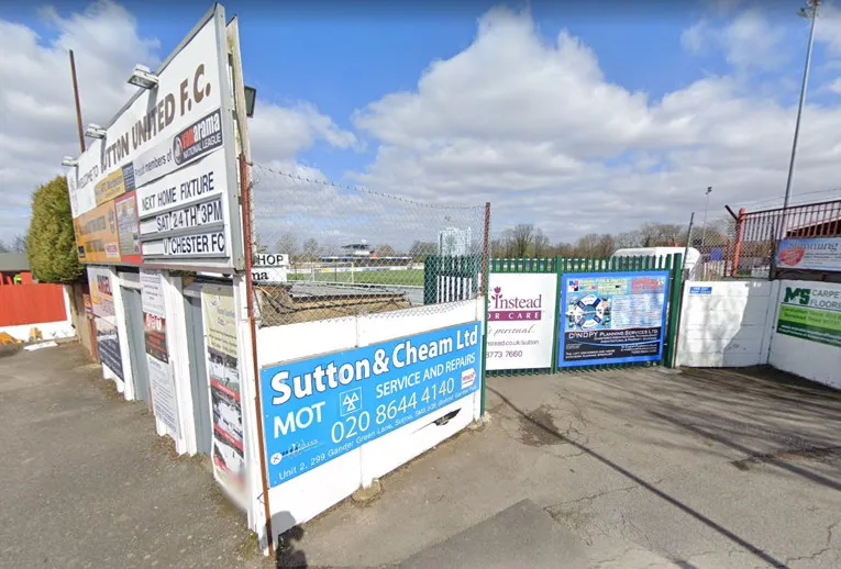 Cổng vào sân Gander Green Lane, chào đón người hâm mộ Sutton United.