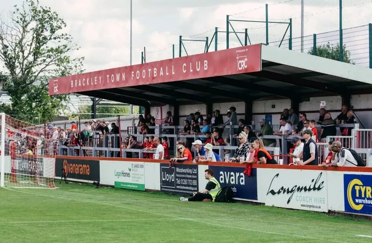 Không khí ngày thi đấu tại St James Park Brackley với cầu thủ trên sân, minh chứng cho sự sống động của bóng đá cấp thấp