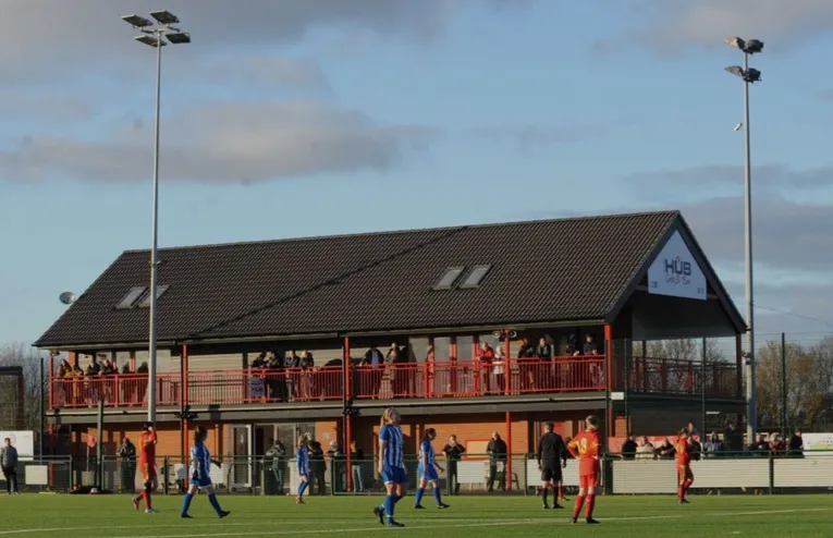 Người hâm mộ Needham Market hào hứng theo dõi trận đấu từ khán đài, thể hiện tinh thần cộng đồng mạnh mẽ tại sân Bloomfields.
