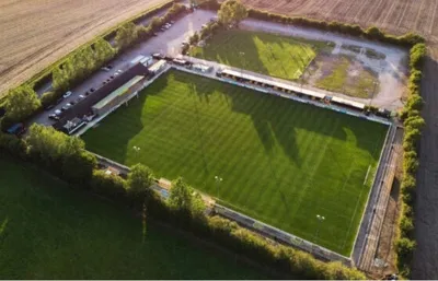 Toàn cảnh sân vận động New Windmill Ground của Leamington FC, nhìn từ trên cao, thể hiện kiến trúc đơn giản nhưng thân thuộc của một sân bóng hạng thấp Anh Quốc.